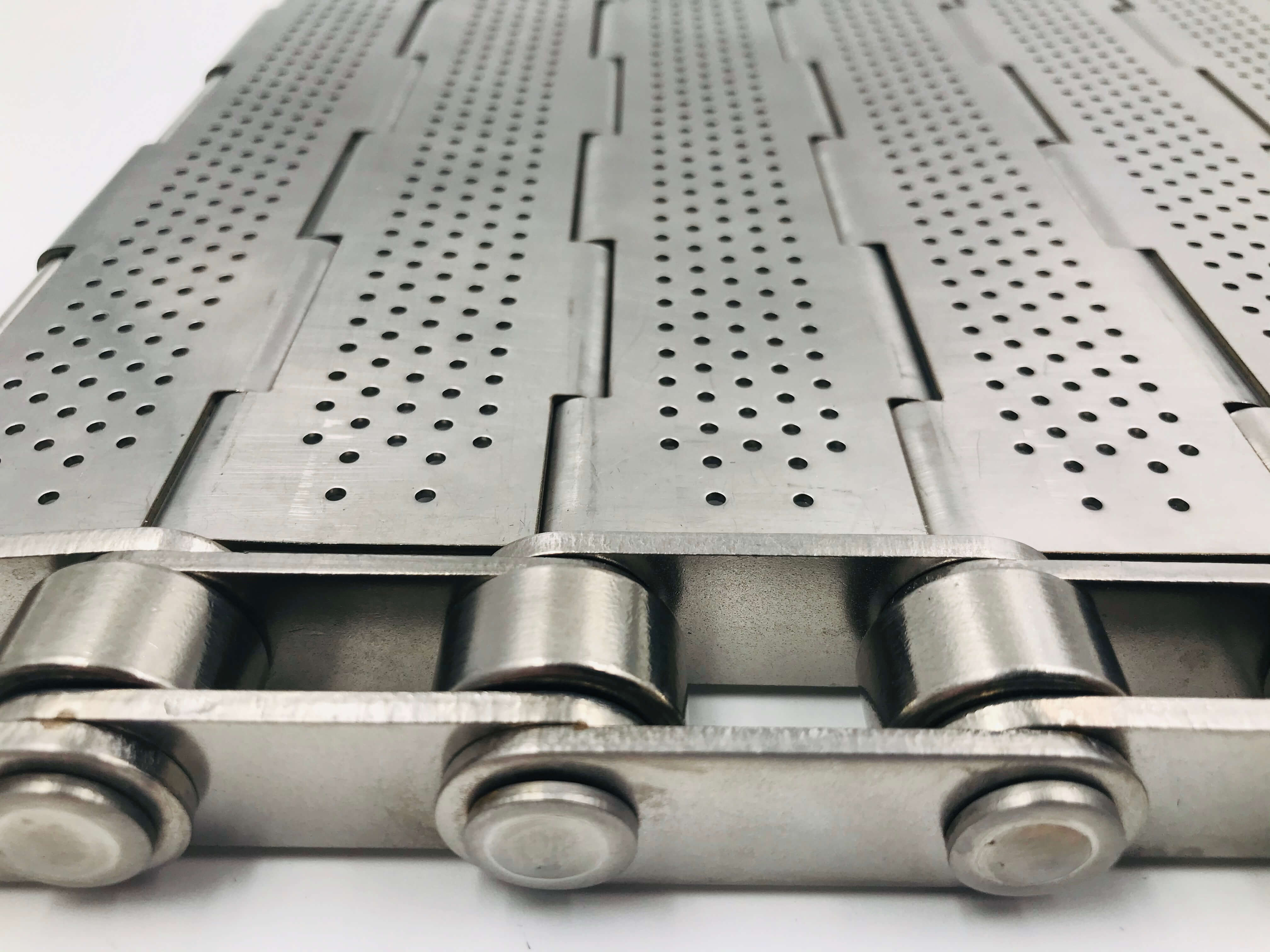 Hinged plate belt with perforated plate surface and raised side guards